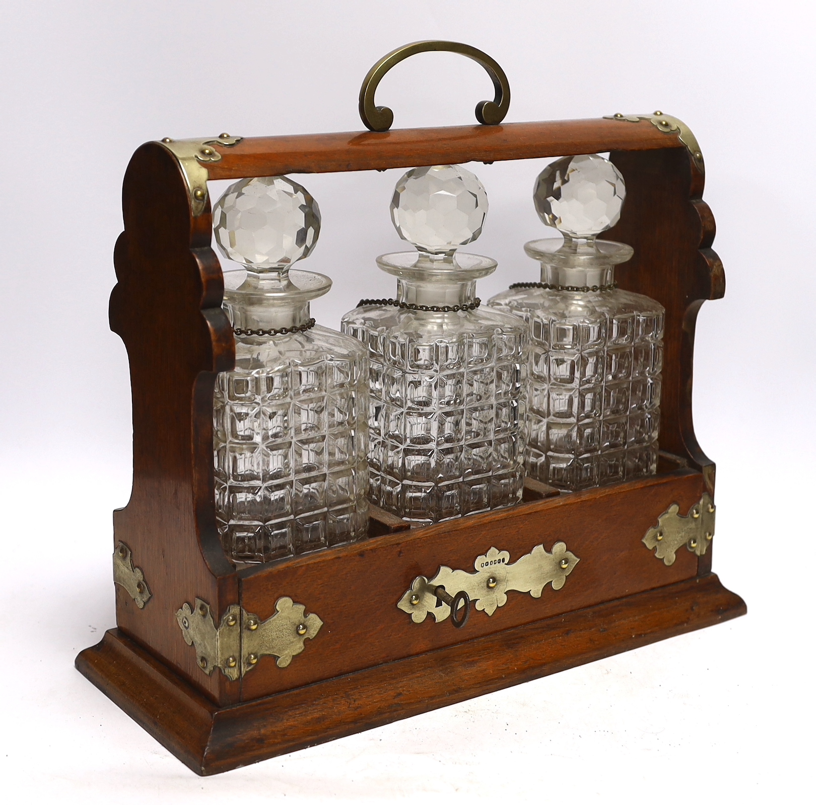 A three bottle tantalus with silver mounts and engraved Masonic presentation, 36cm wide